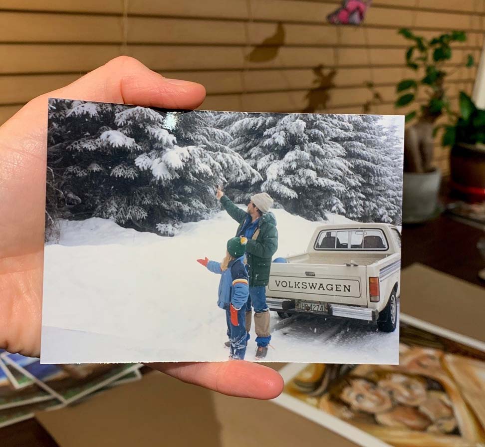father and daughter feeding the birds in the snow by a volkswagen pickup truck